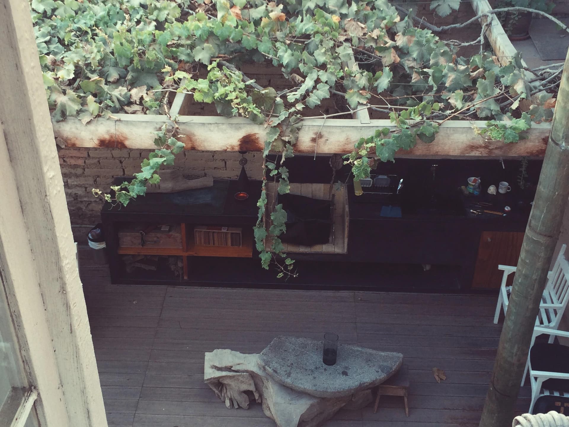 A scenic view of a patio seen from an upstairs window, showcasing outdoor furniture and greenery.